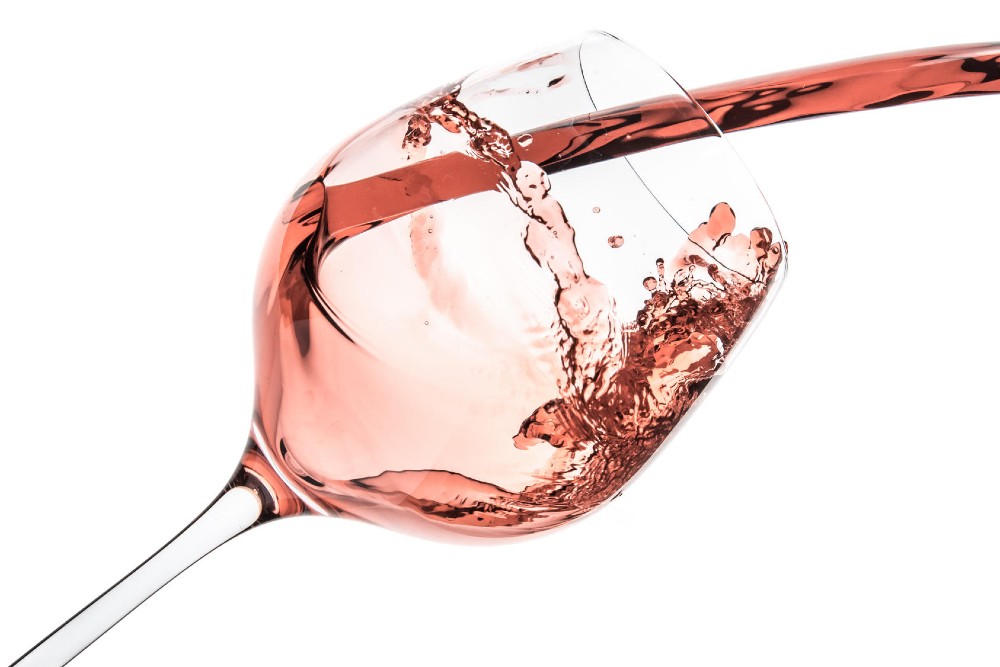 Vinho rosé com sua cor característica sendo servido em uma taça. 