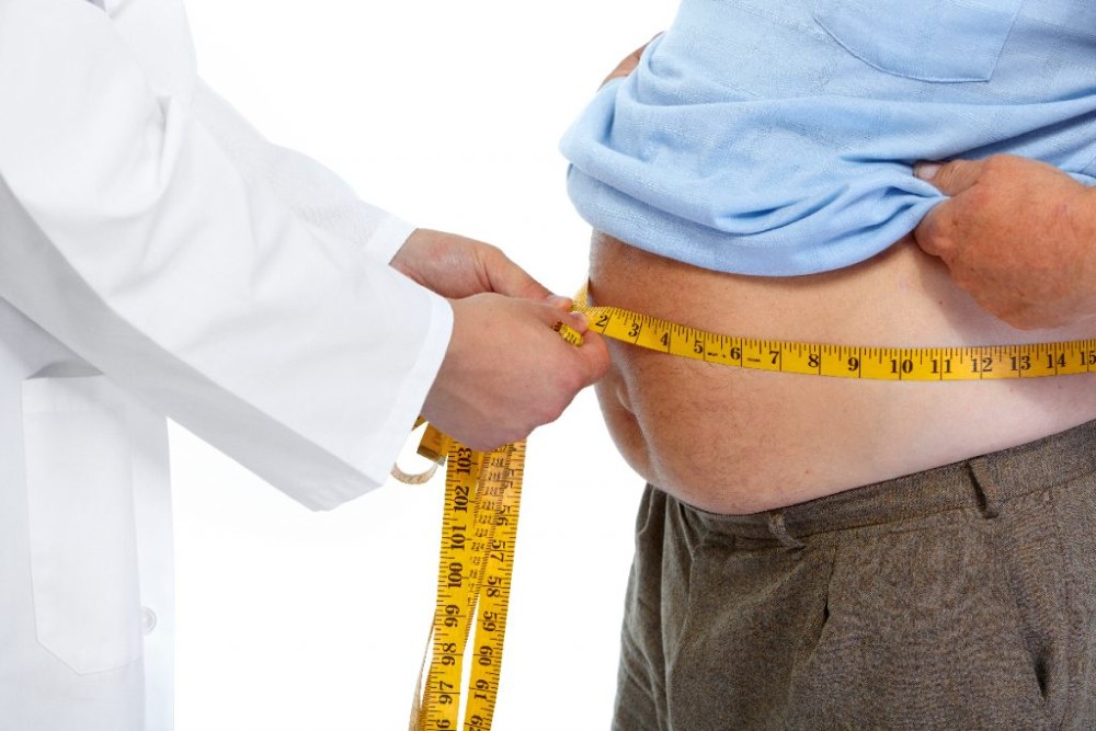 Imagem de fita métrica medindo uma barriga de homem de meia-idade